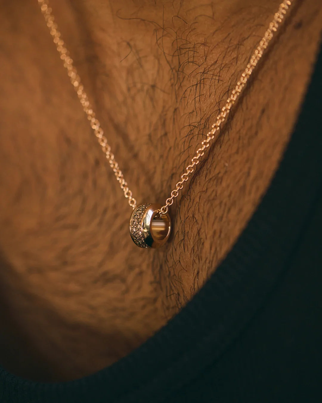 Prevaut men’s necklaces; close-up chest shot of 18k rose gold pendant ring with cognac diamonds on chain