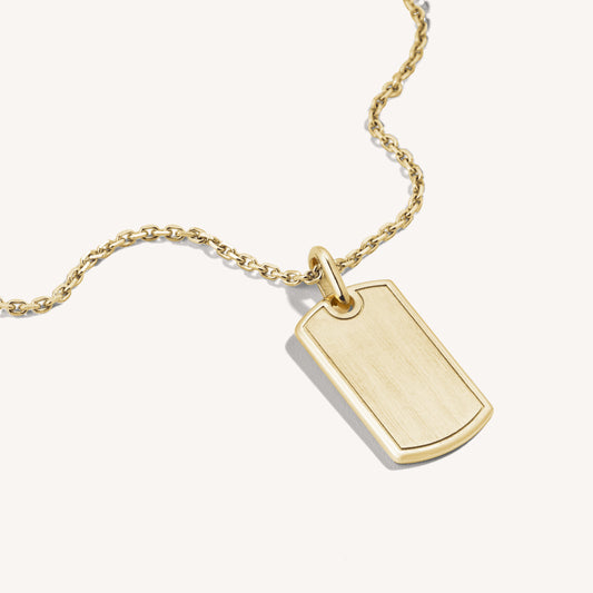 A 18k rose gold dog tag necklace with a beveled edge and brushed center, suspended from a gold chain.