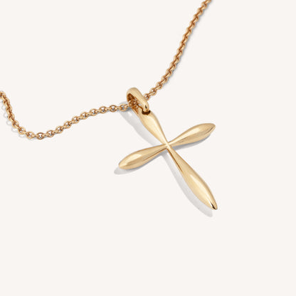 A polished 18-karat rose gold cross pendant on a chain, showcasing smooth surfaces and sharp edges with a lustrous finish.