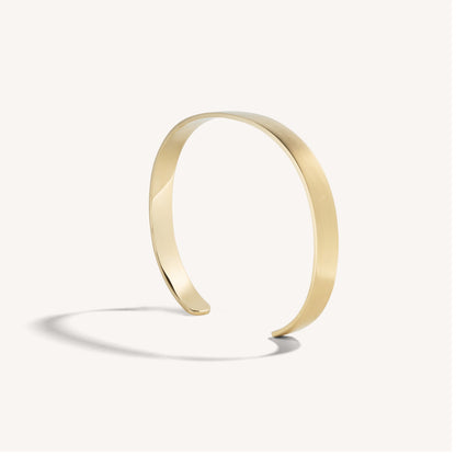 Men’s brushed 18k yellow gold open cuff bracelet with rounded edges, on white background.