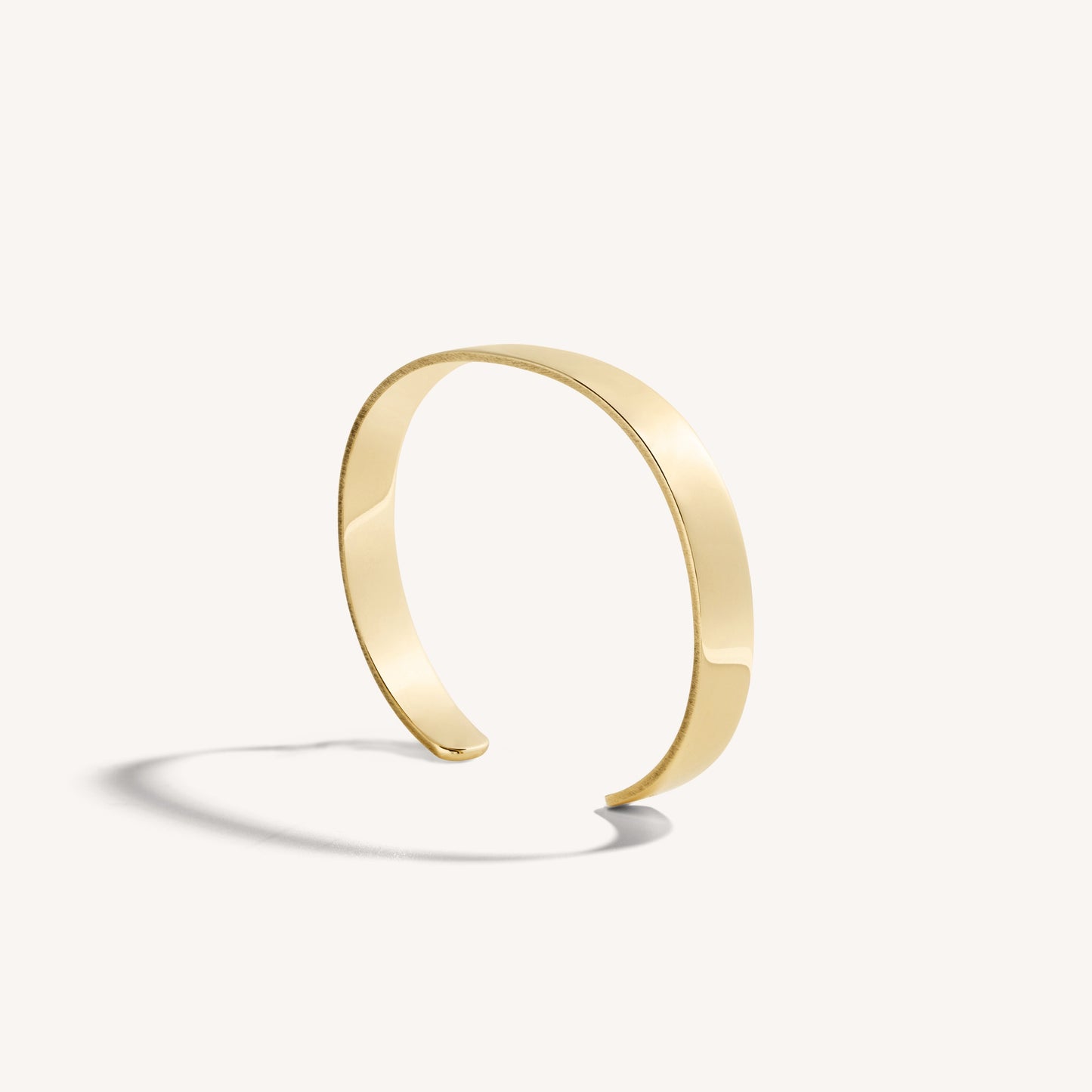 Men’s polished 18k yellow gold open cuff bracelet with rounded edges, on white background.