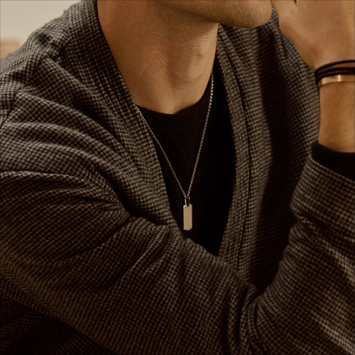 18k white gold Dog tag pendant necklace worn with a dark top and checked jacket