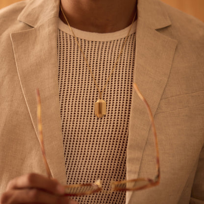 Faceted 18k rose gold pendant necklace worn over a textured knit top and light blazer