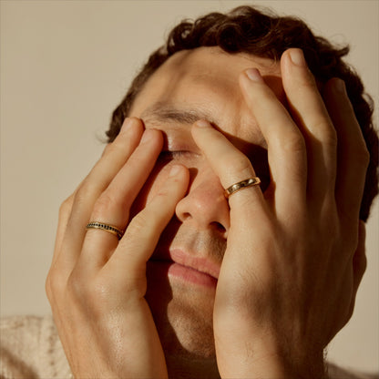 Close-up portrait with hands on face wearing two 18k gold band rings