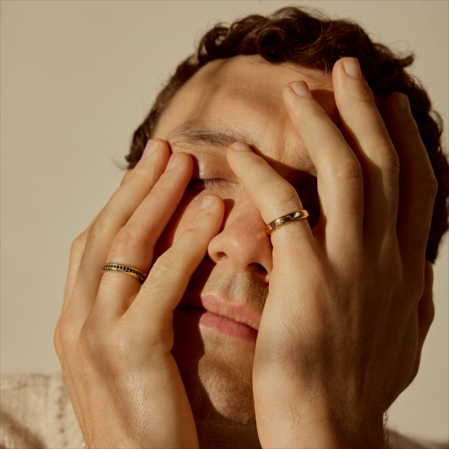 Close-up portrait with hands on face wearing two 18k gold band rings
