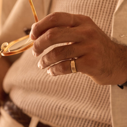 18k yellow gold beveled band ring worn on hand holding eyeglasses