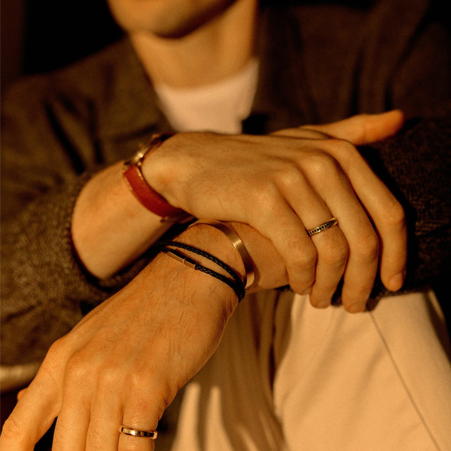 18k rose gold cuff bracelet worn with black leather bracelet and 18k yellow gold band rings