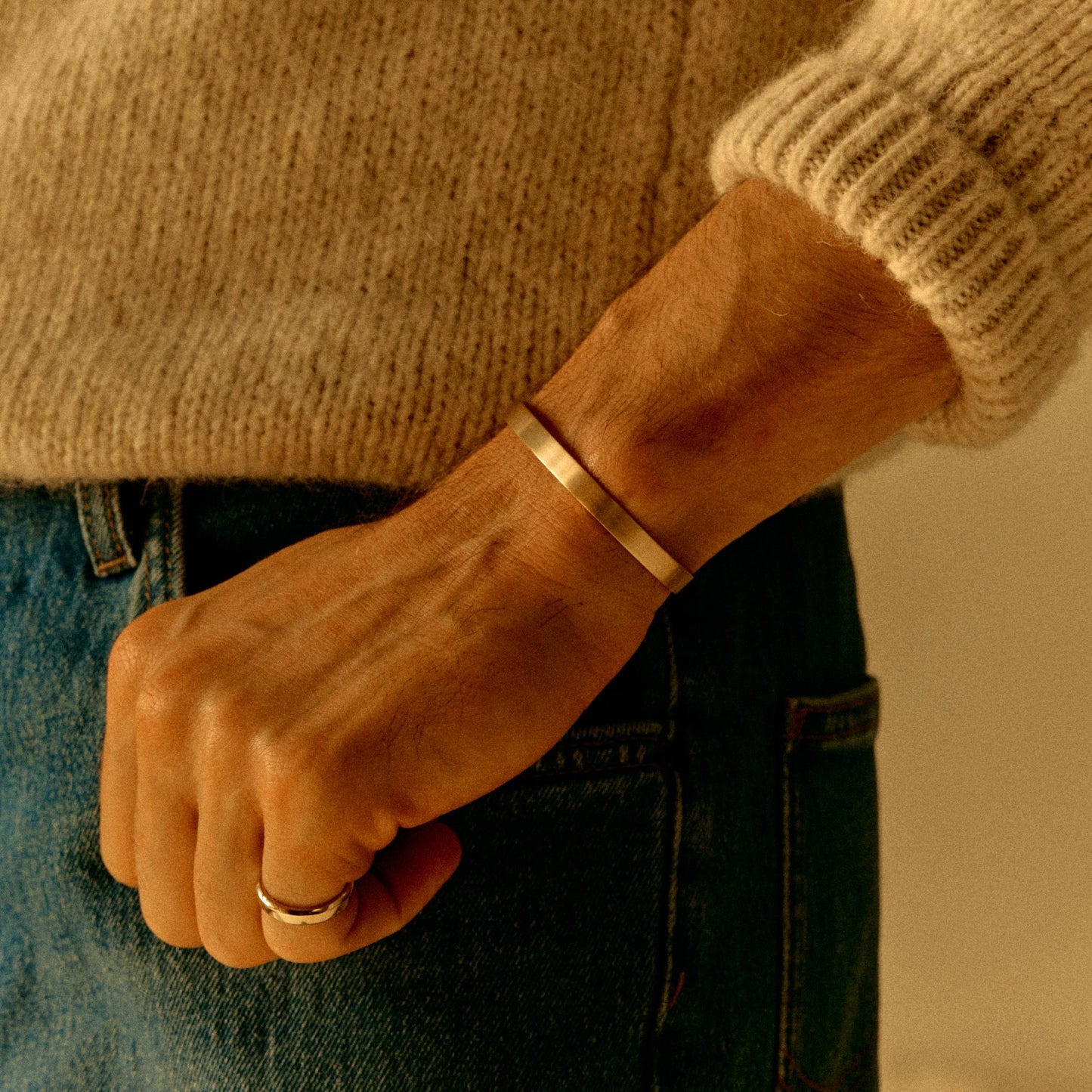 18k rose gold cuff bracelet worn on wrist with knit sleeve
