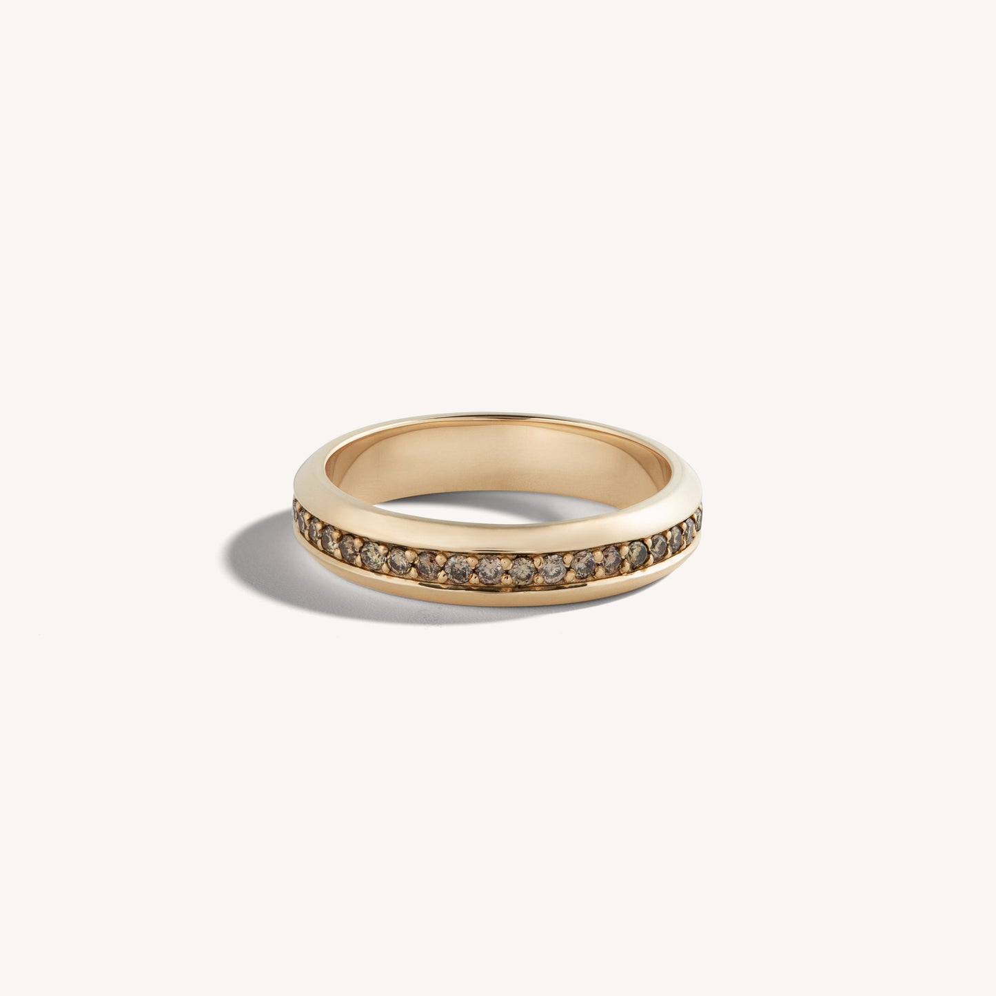 Slim 18k rose gold ring with continuous cognac diamond channel, flat-lay on neutral backdrop.
