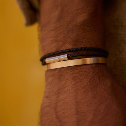 Black double-wrap hexagonal leather bracelet with 18k rose-gold clasp on wrist.
